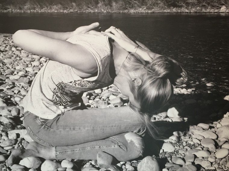 Monika Schindlbeck in Yoga Haltung sitzend an der Isar